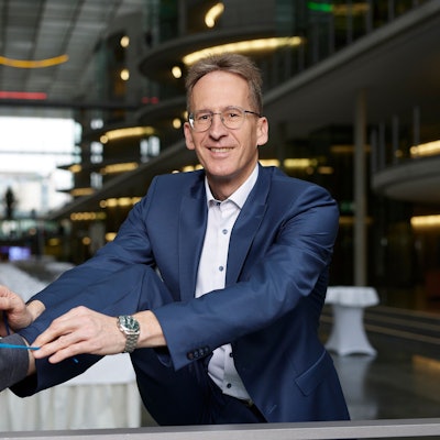 Das Bild zeigt Detlef Seif, der sich im Anzug einen Turnschuh bindet.