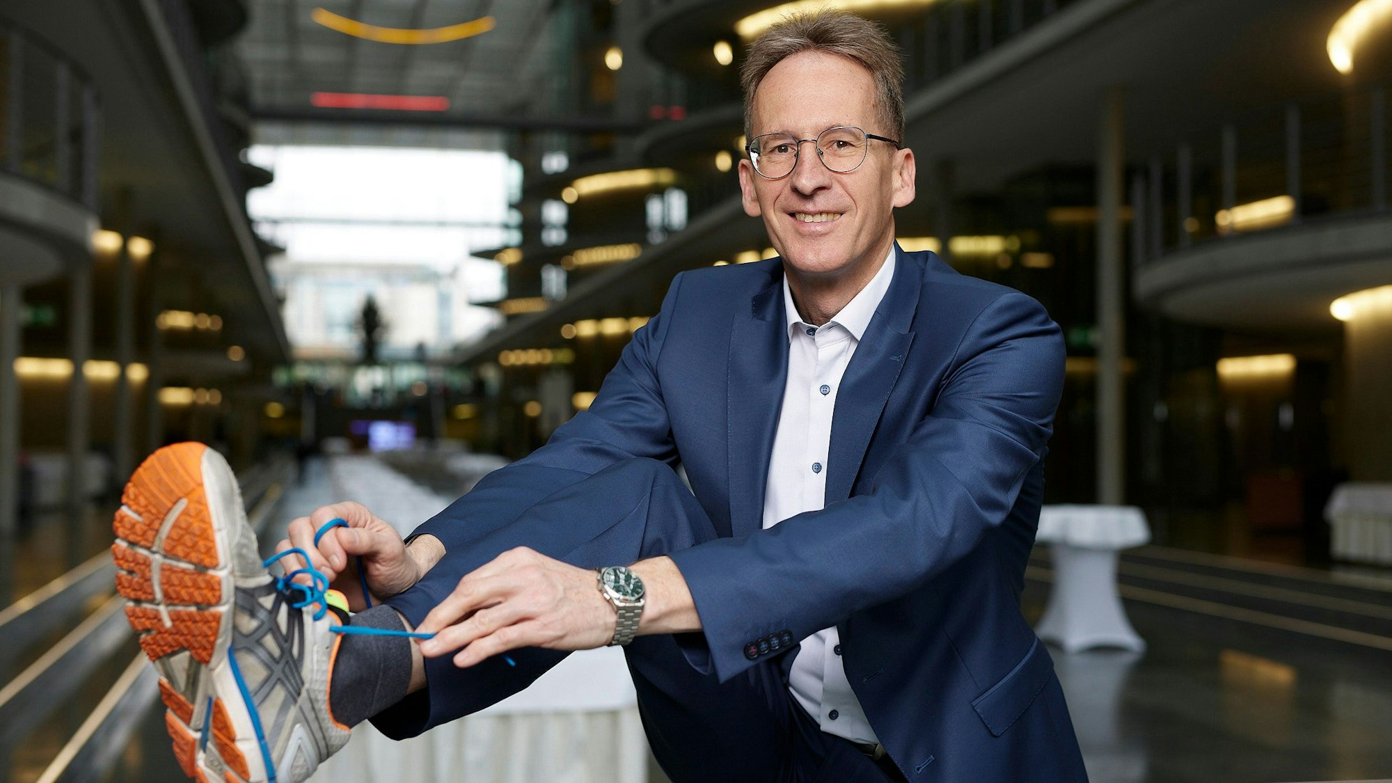 Das Bild zeigt Detlef Seif, der sich im Anzug einen Turnschuh bindet.