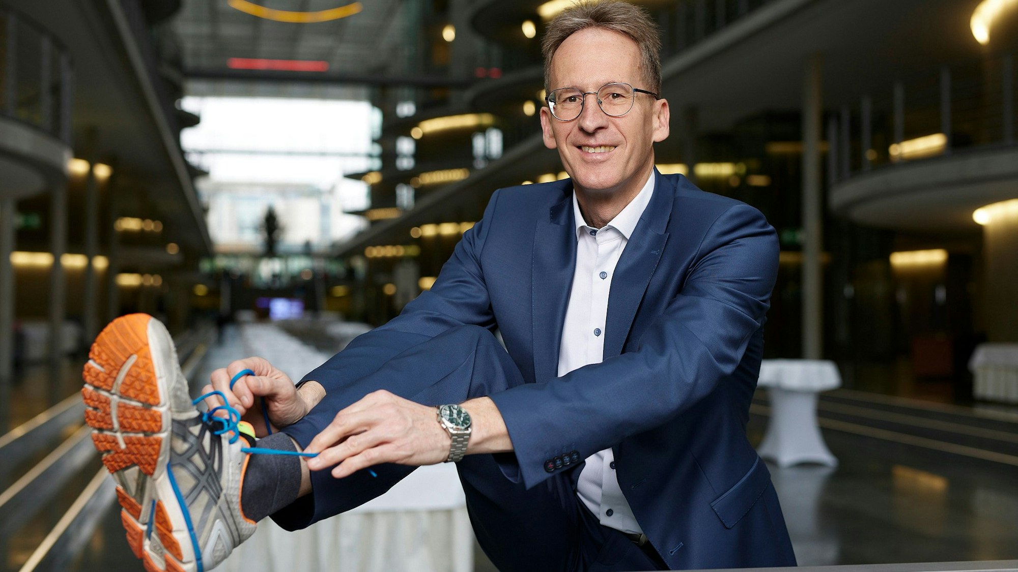 Das Foto zeigt den CDU-Bundestagsabgeordneten Detlef Seif. Er trägt einen Anzug und bindet sich einen Joggingschuh zu.