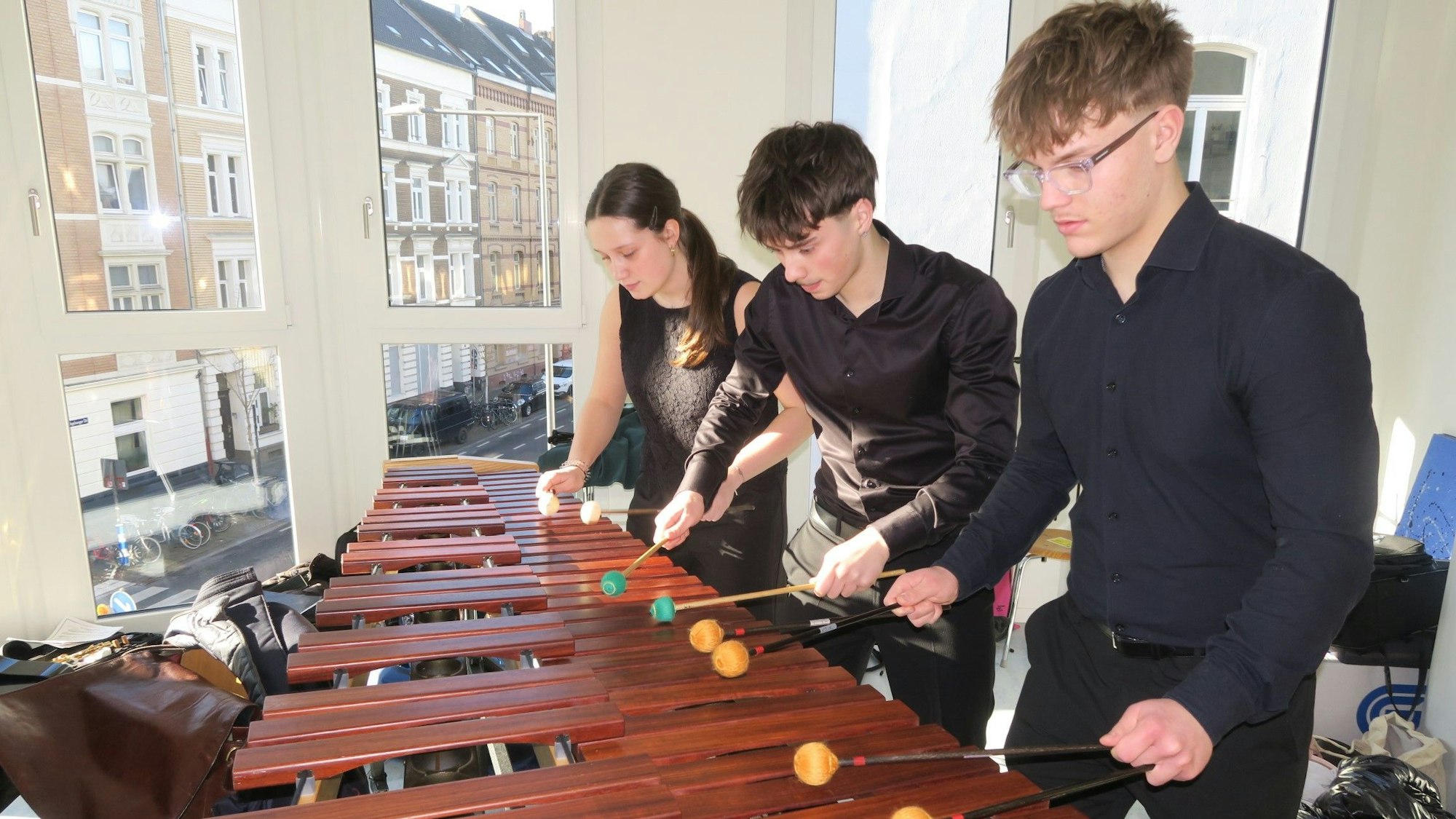Ein Mädchen und zwei Jungs spielen zu dritt ein Marimbaphon.