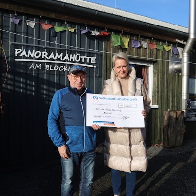 Bernhard Junge übergibt vor der Panoramahütte am Blockhaus eine Spende an Bettina Hühn.