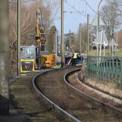 Große Betonklötze stehen neben einer Stadtbahntrasse, im Hintergrund stehen Baumaschinen