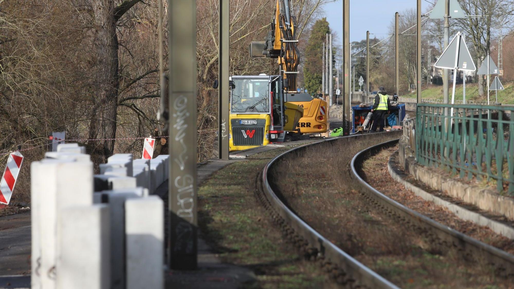 Große Betonklötze stehen neben einer Stadtbahntrasse, im Hintergrund stehen Baumaschinen