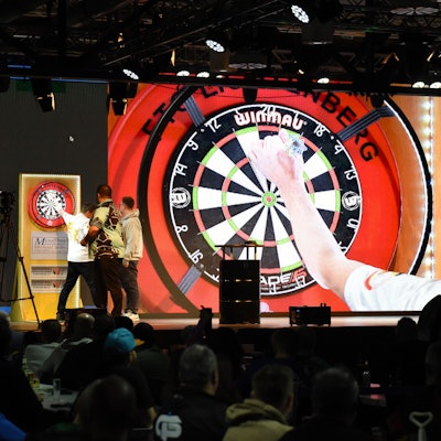 Eine Dartscheibe wird auf einer Leinwand in Großaufnahme gezeigt.