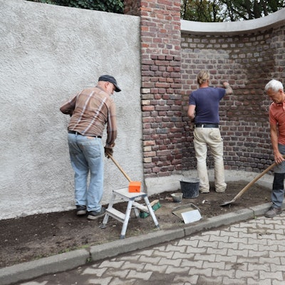 Vier Männer sanieren eine Fridhofsmauer.