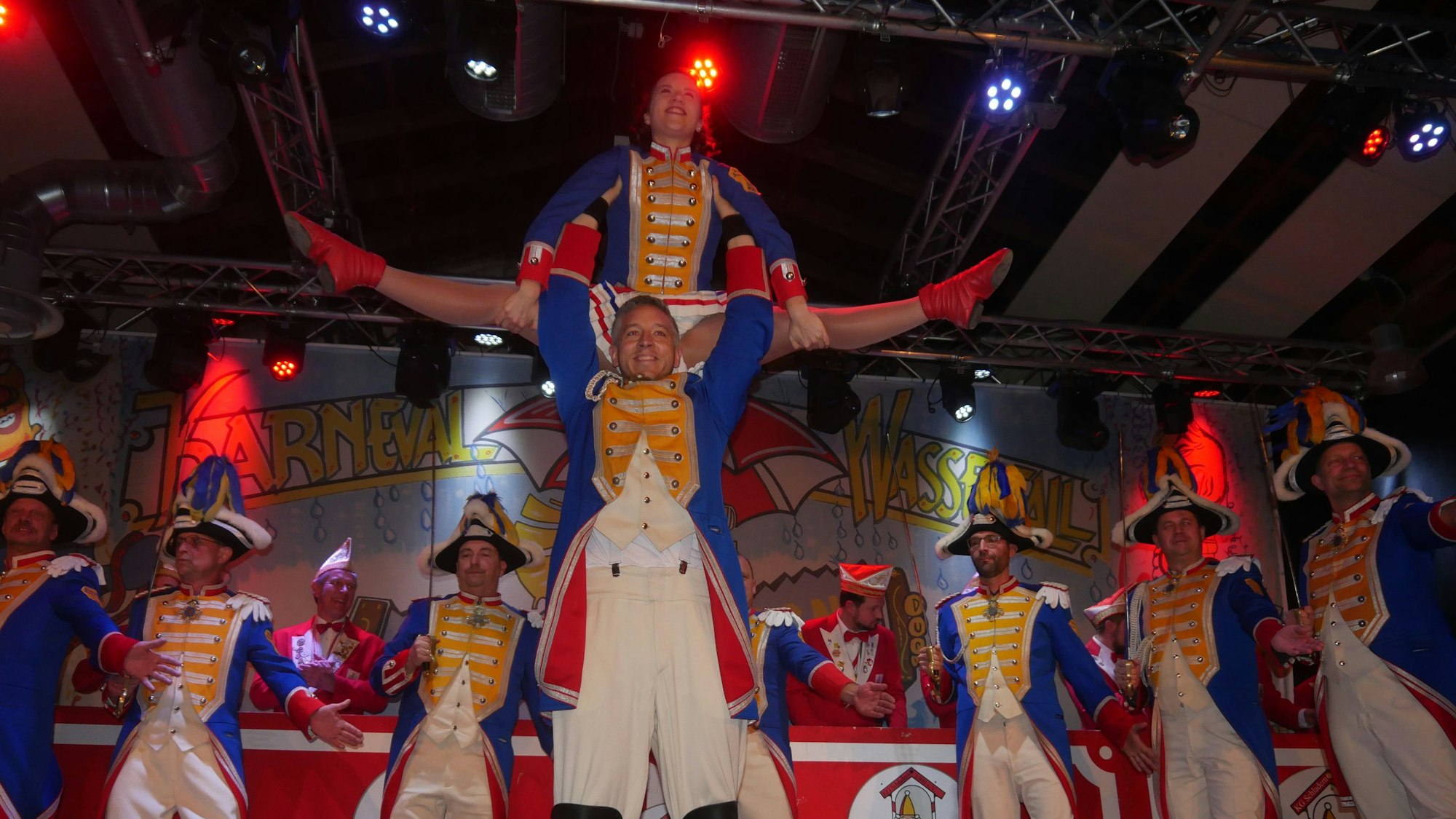 Eine Karnevalstanzgruppe; das Funkenmariechen mnacht Spagat in einer Hebefigur.