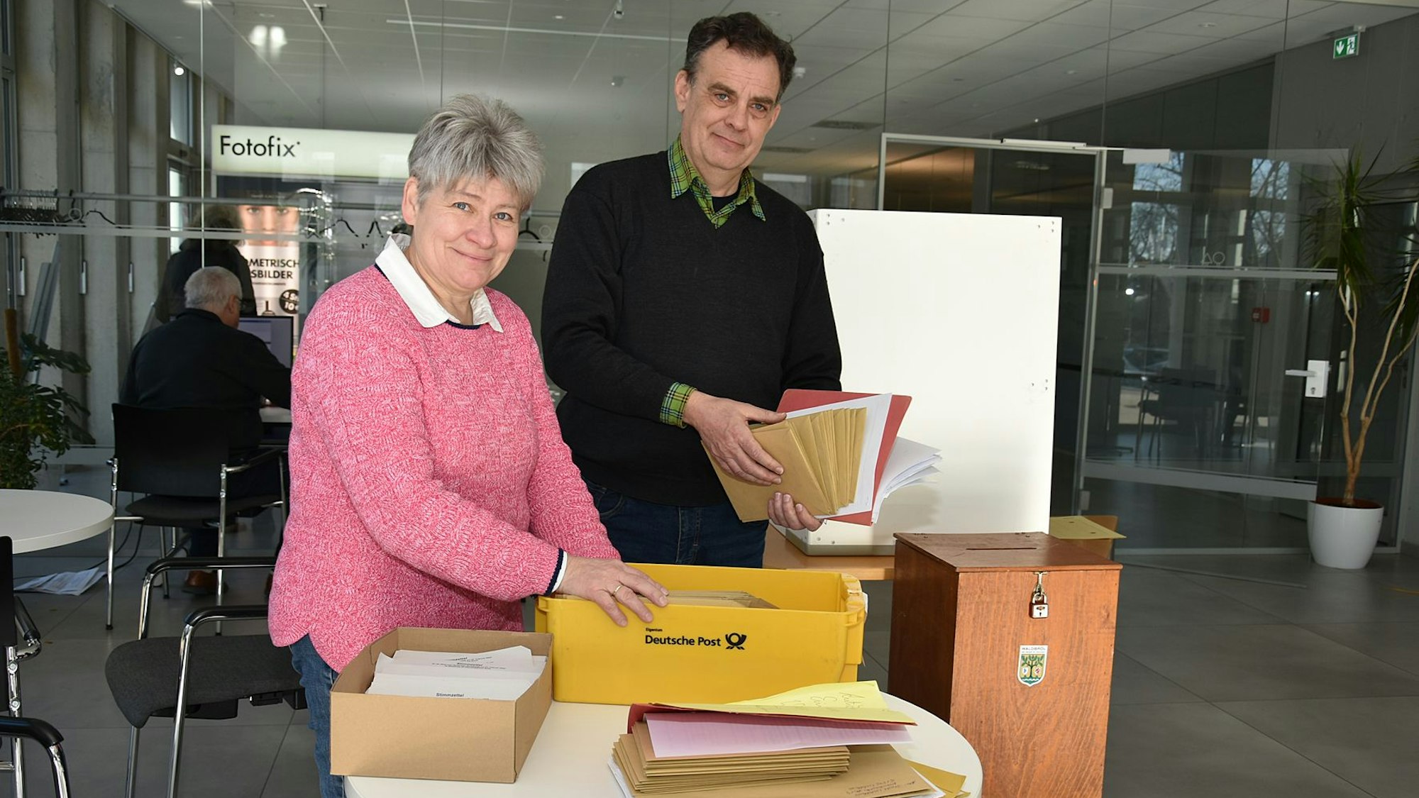 Eine Frau und ein Mann hantieren mit Briefumschlägen.