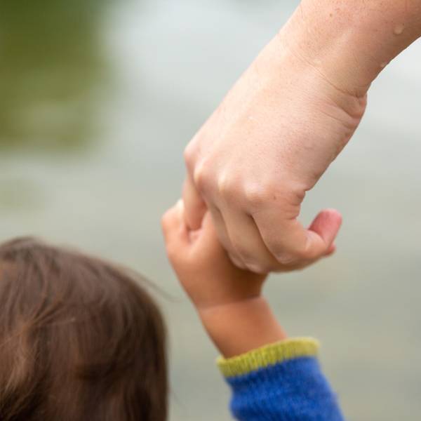 Ein Kind hält die Hand eines Erwachsenen.