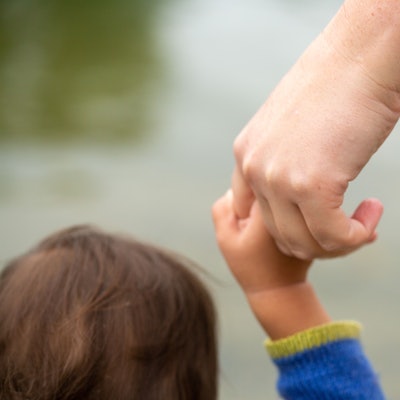 Ein Kind hält die Hand eines Erwachsenen.