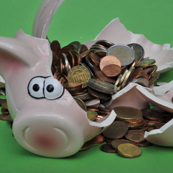Eine Sparschwein mit Euro-Geldstücken liegt zerbrochen da.