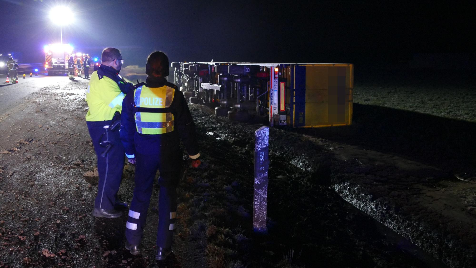 Polizisten stehen vor einem ungekippten Lkw.