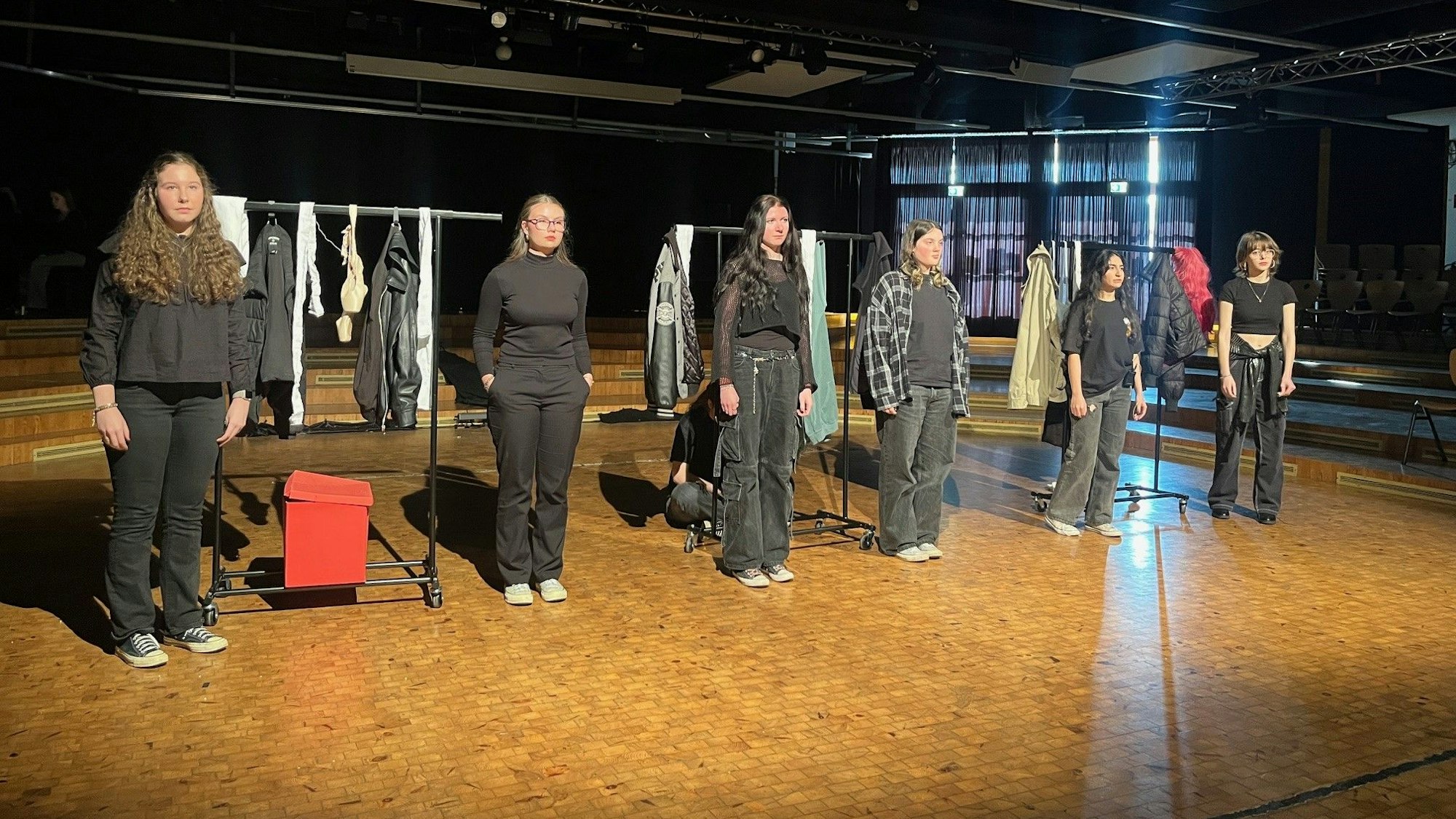 Sechs junge Frauen stehen auf einer Bühne und spielen Theater.