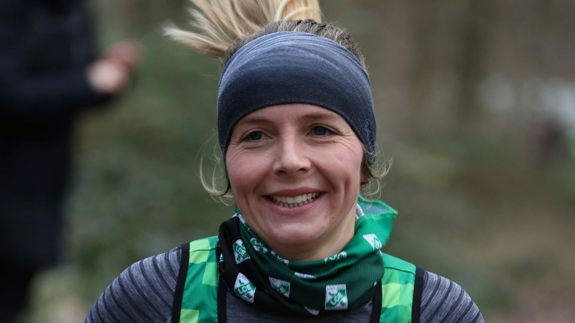 Nora Schmitz trägt beim Laufen ein Stirnband, das auch die Ohren bedeckt. Ihr blonder Zopf fliegt in die Höhe. Sie lächelt.