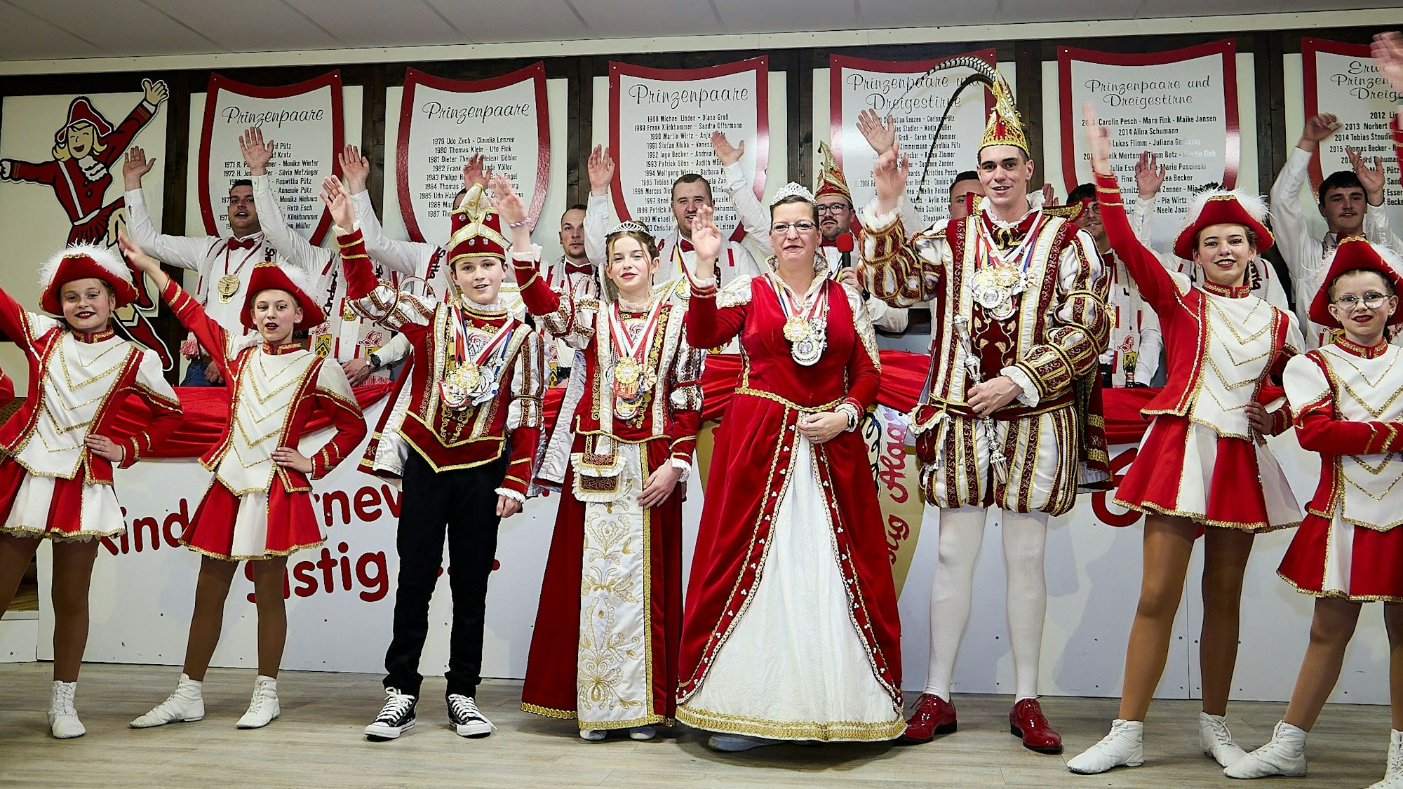 Auf der Bühne stehen die Sistiger Tollitäten in vollem Ornat und heben ihre rechten Arme zum Alaaf-Ruf.