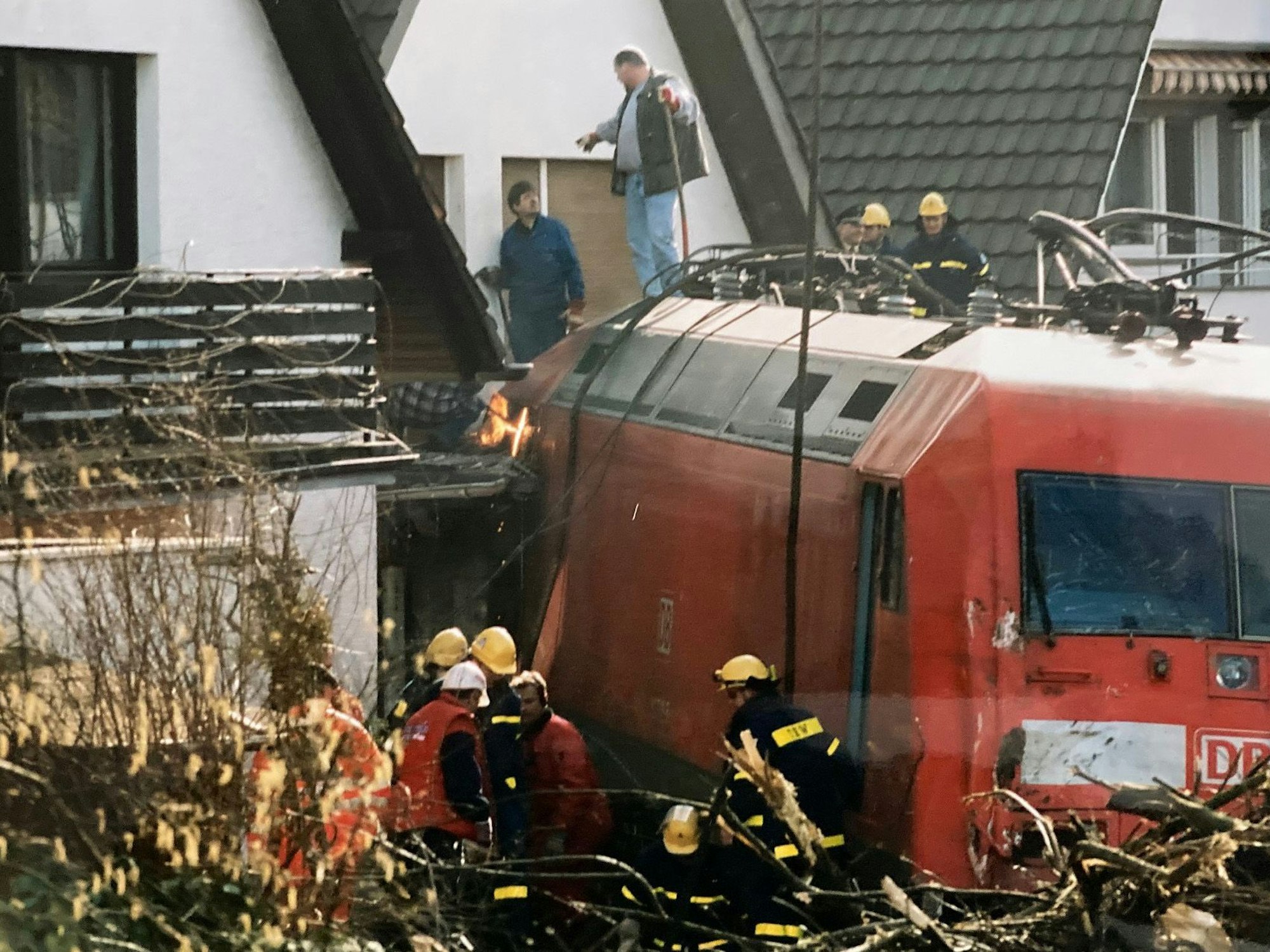Das Bild zeigt eine rote Lok, die an einem Einfamilienhaus steht.