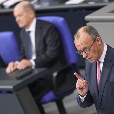 Bundeskanzler Olaf Scholz (SPD) hört Friedrich Merz (r), CDU Bundesvorsitzender und CDU/CSU Fraktionsvorsitzender im Bundestag, zu, als dieser bei der Debatte um das Zustrombegrenzungsgesetz im Plenarsaal im Bundestag spricht.