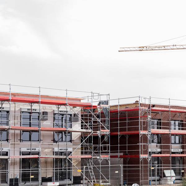 Häuser stehen eingerüstet auf einem Baufeld am Stadtrand von Köln.