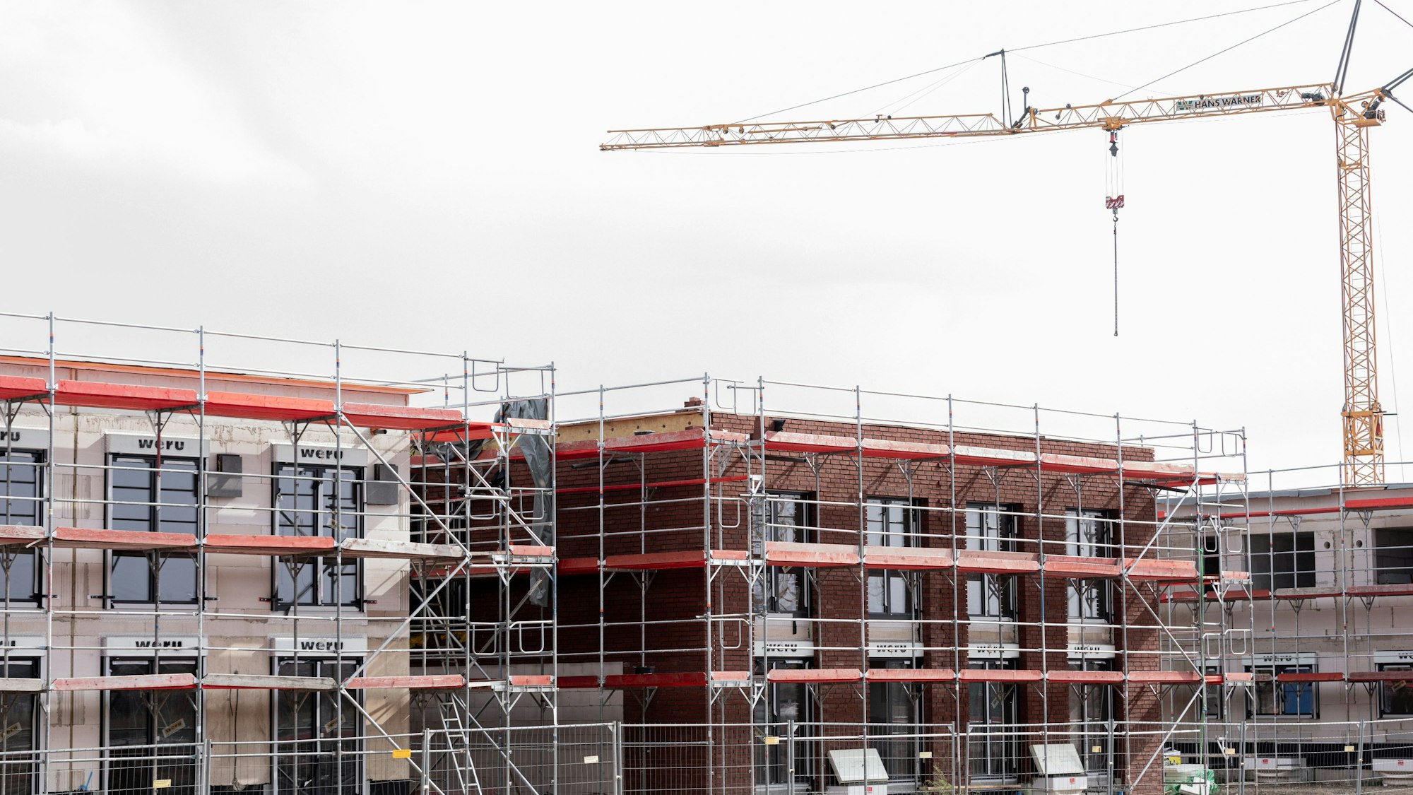 Häuser stehen eingerüstet auf einem Baufeld am Stadtrand von Köln.