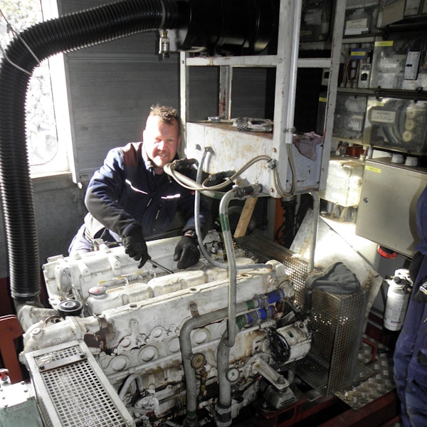 Ein Mann in Arbeitskleidung und Handschuhen ist im Maschinenraum des Rurseeschiffs Aachen und schraubt am Motor.
