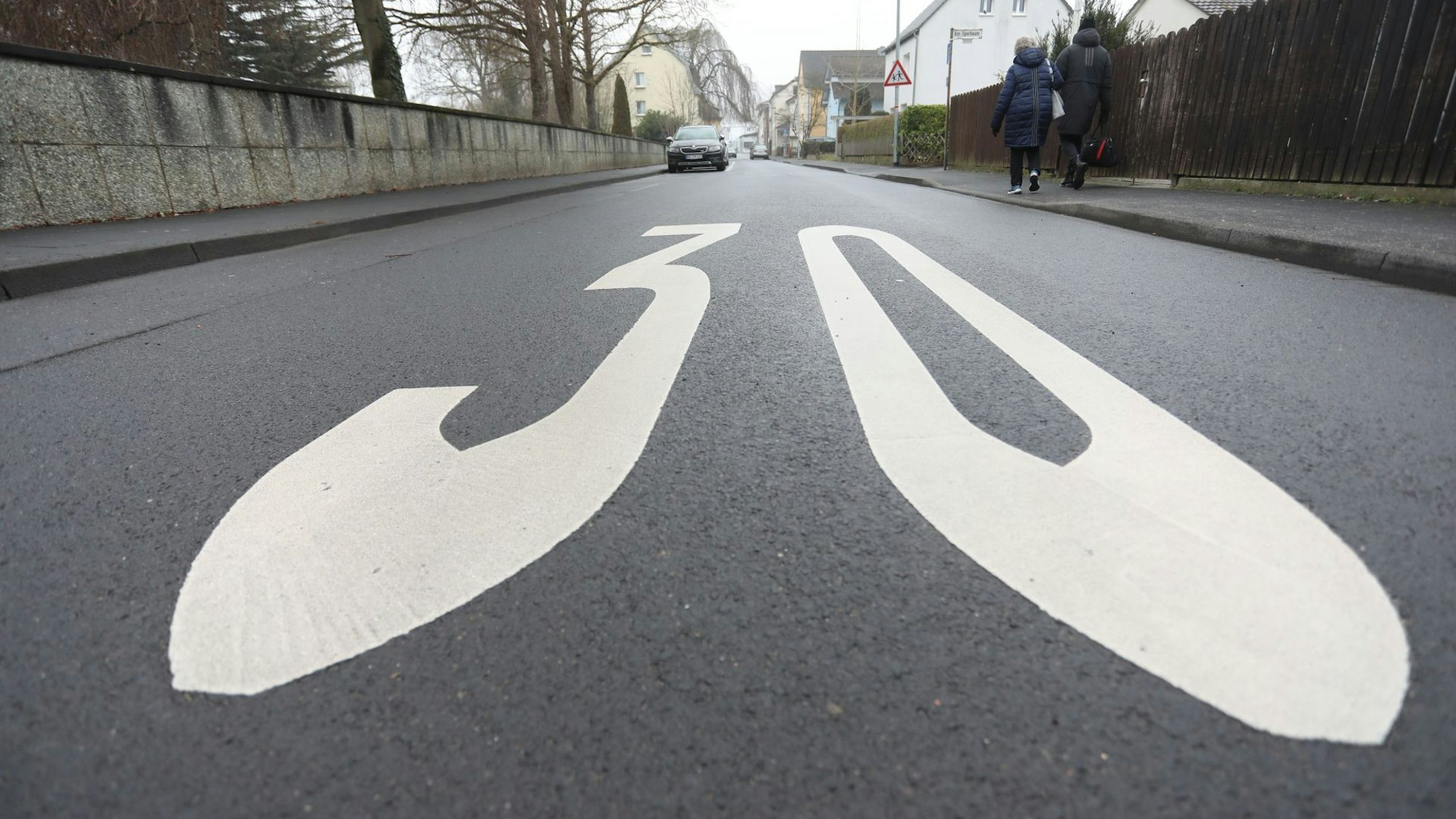 Die Zahl 30 ist groß in Weiß auf die Fahrbahn einer Straße gemalt.