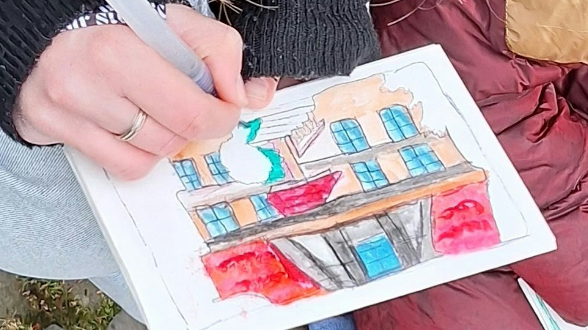 Nahaufnahme von einer kolorierten Skizze, an der eine Hand mit einem Stift zeichnet