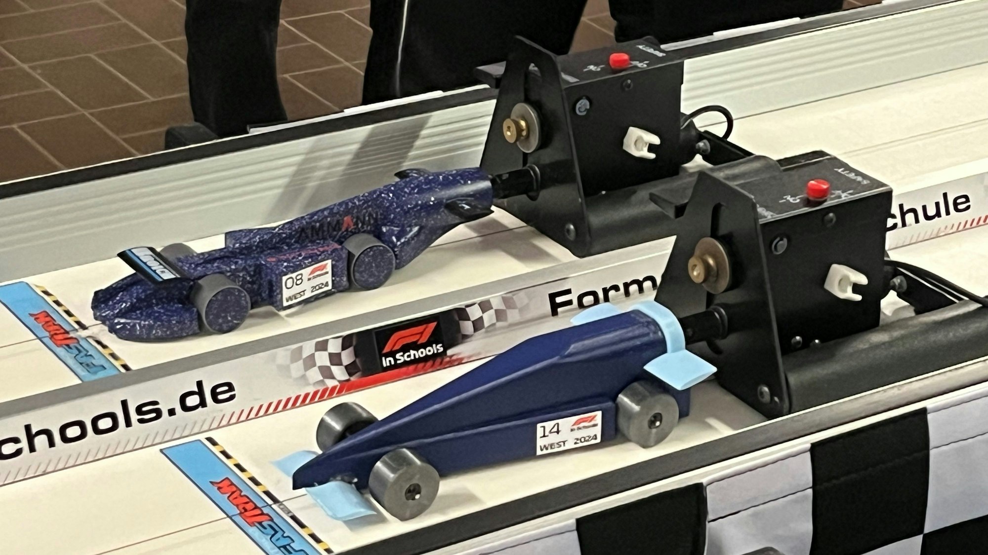 Zwei Miniatur-Rennwagen stehen auf einer Fahrbahn.