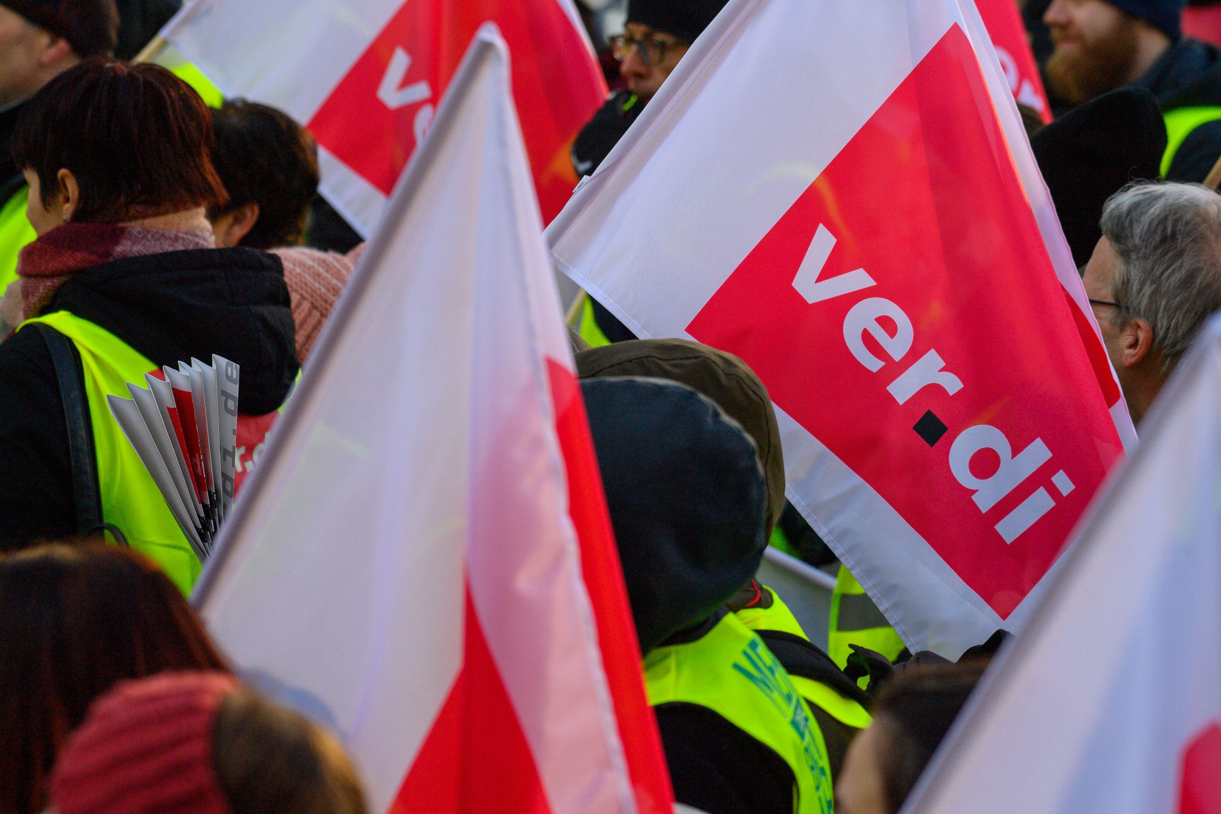 Das Foto zeigt Teilnehmer einer Demo, die Verdi-Fahnen tragen.