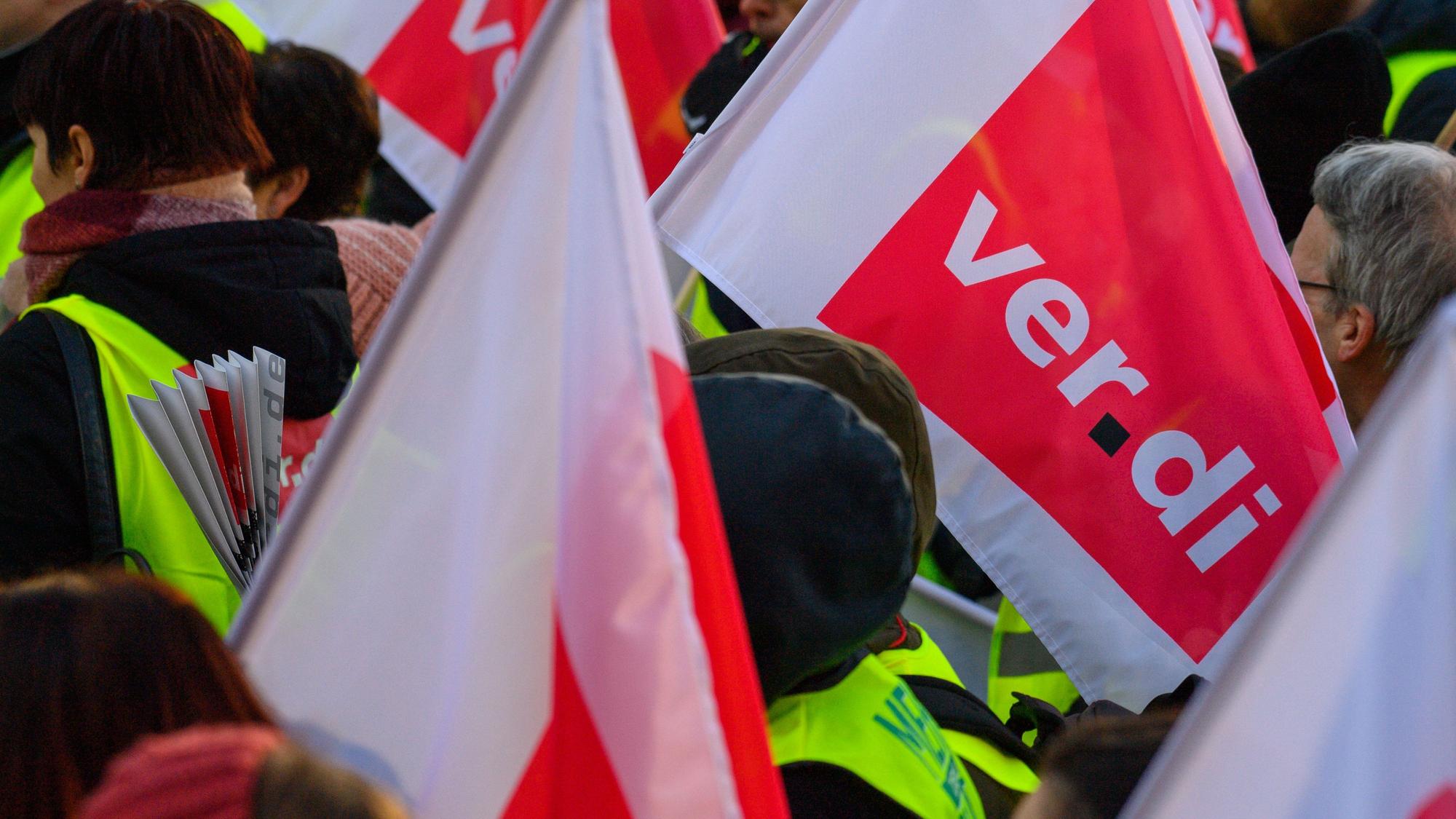 Das Foto zeigt Teilnehmer einer Demo, die Verdi-Fahnen tragen.