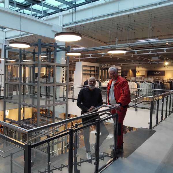 Zwei Männer stehen an einer Treppe in einem Kaufhaus