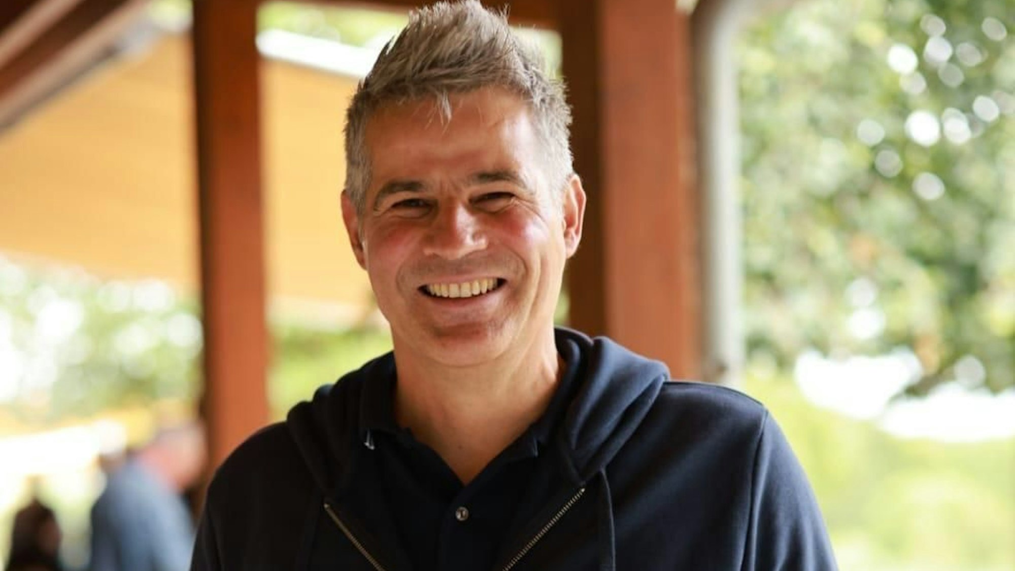 In lächelnder Mann mit hochgegeltem Haar.