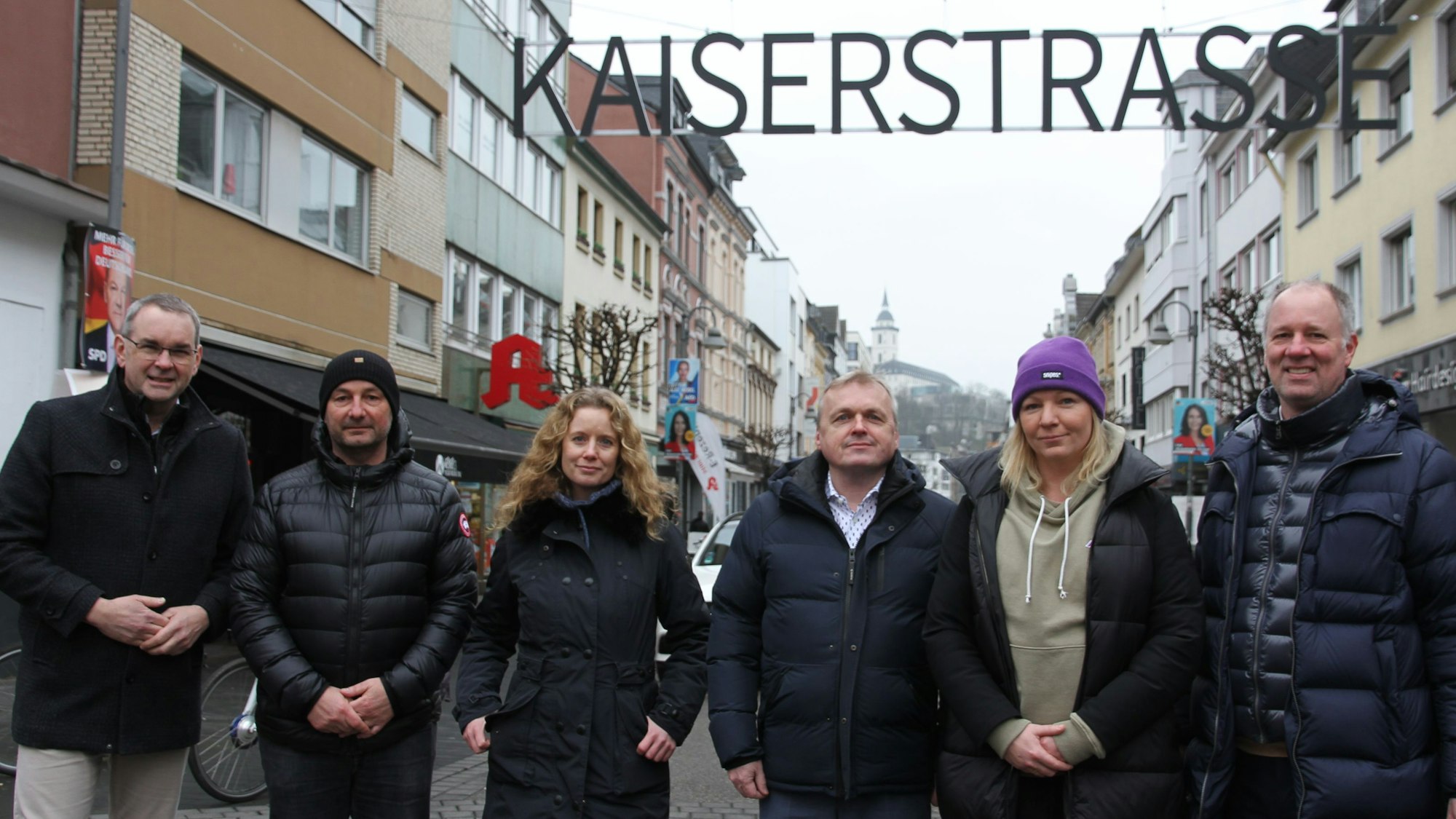 Vier Männer und zwei Frauen in einer Einkaufsstraße.