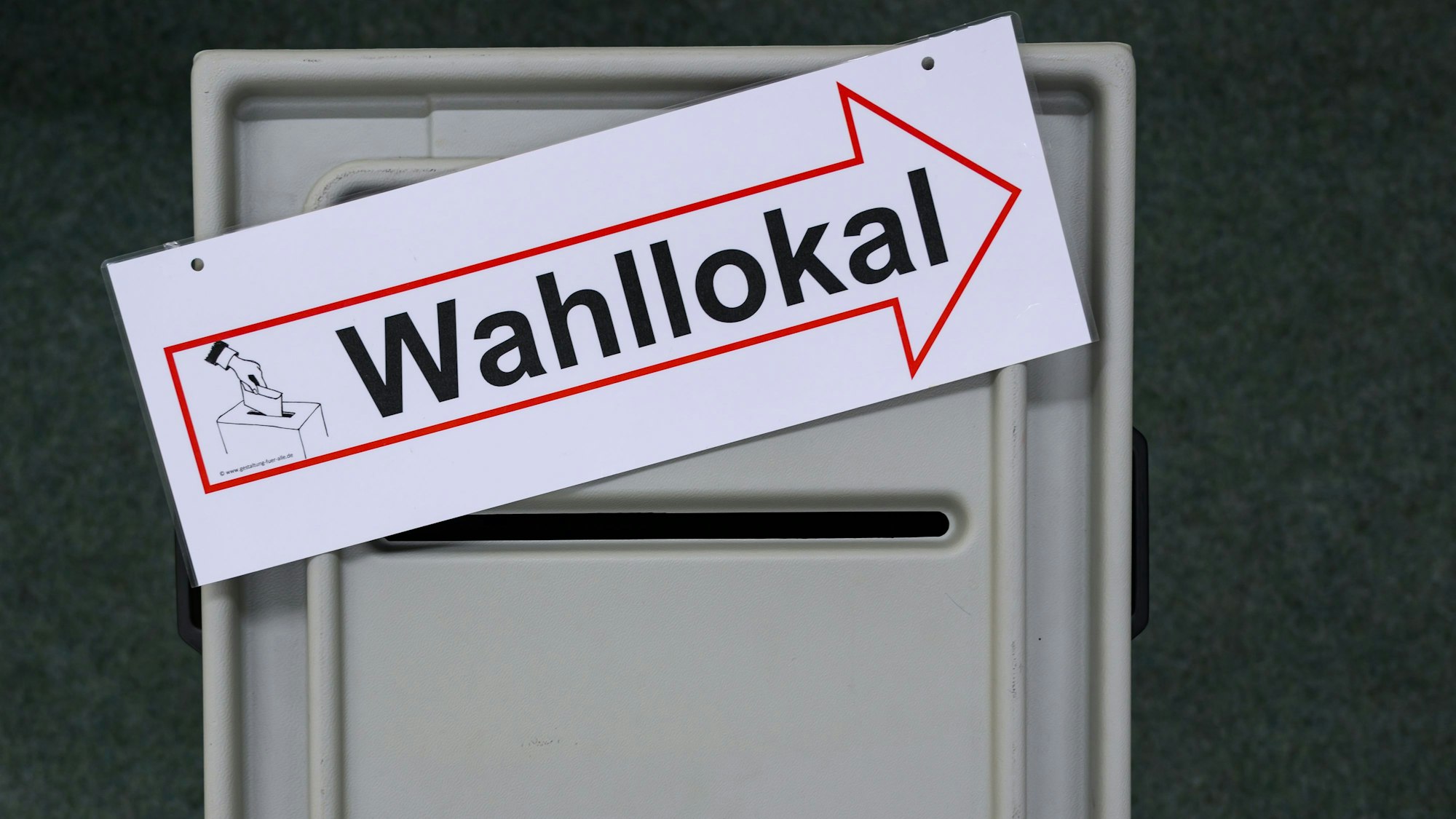 In einem Raum einer Wahlleitung liegt ein Schild mit der Aufschrift Wahllokal auf einer Wahlurne.