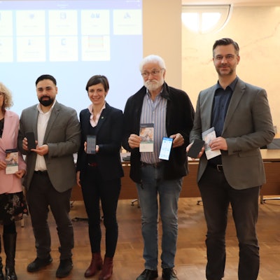 Männer und Frauen stehen vor einer Leinwand.