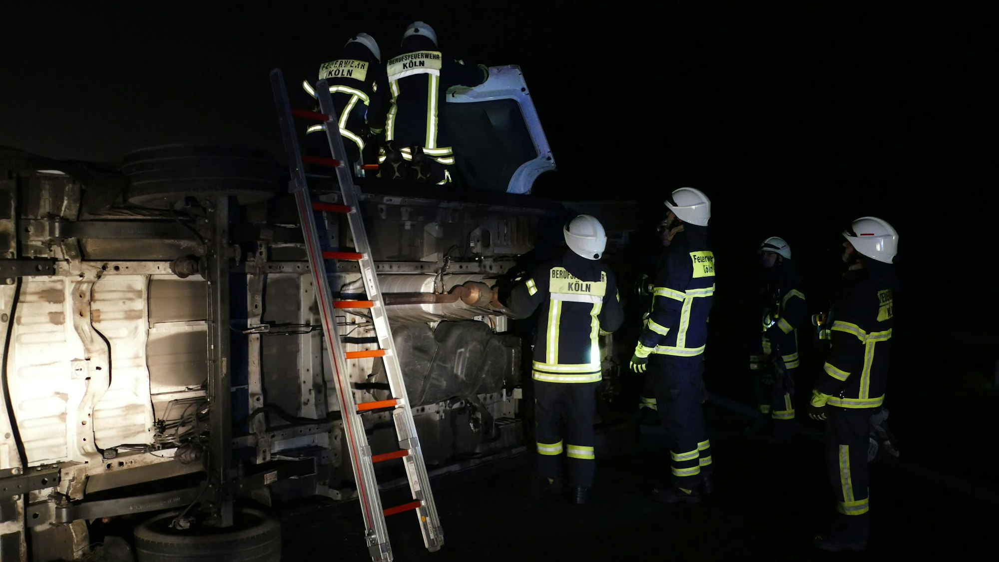 Feuerwehrleute stehen auf einem auf der Seite liegenden Transporter.
