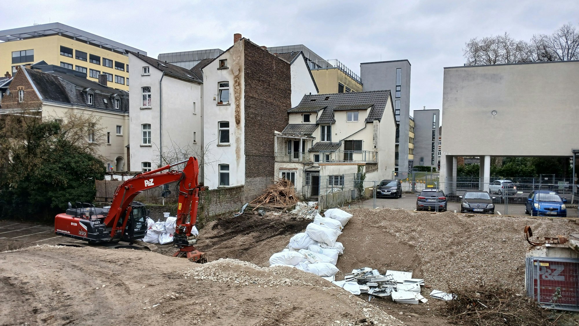 Ein Bagger vor einem Graben und einer Häuserzeile.