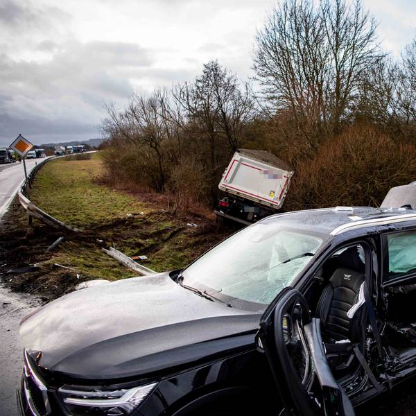 Das Bild zeigt ein stark beschädigtes Auto. Im Hintergrund liegt ein Sattelschlepper im Graben.
