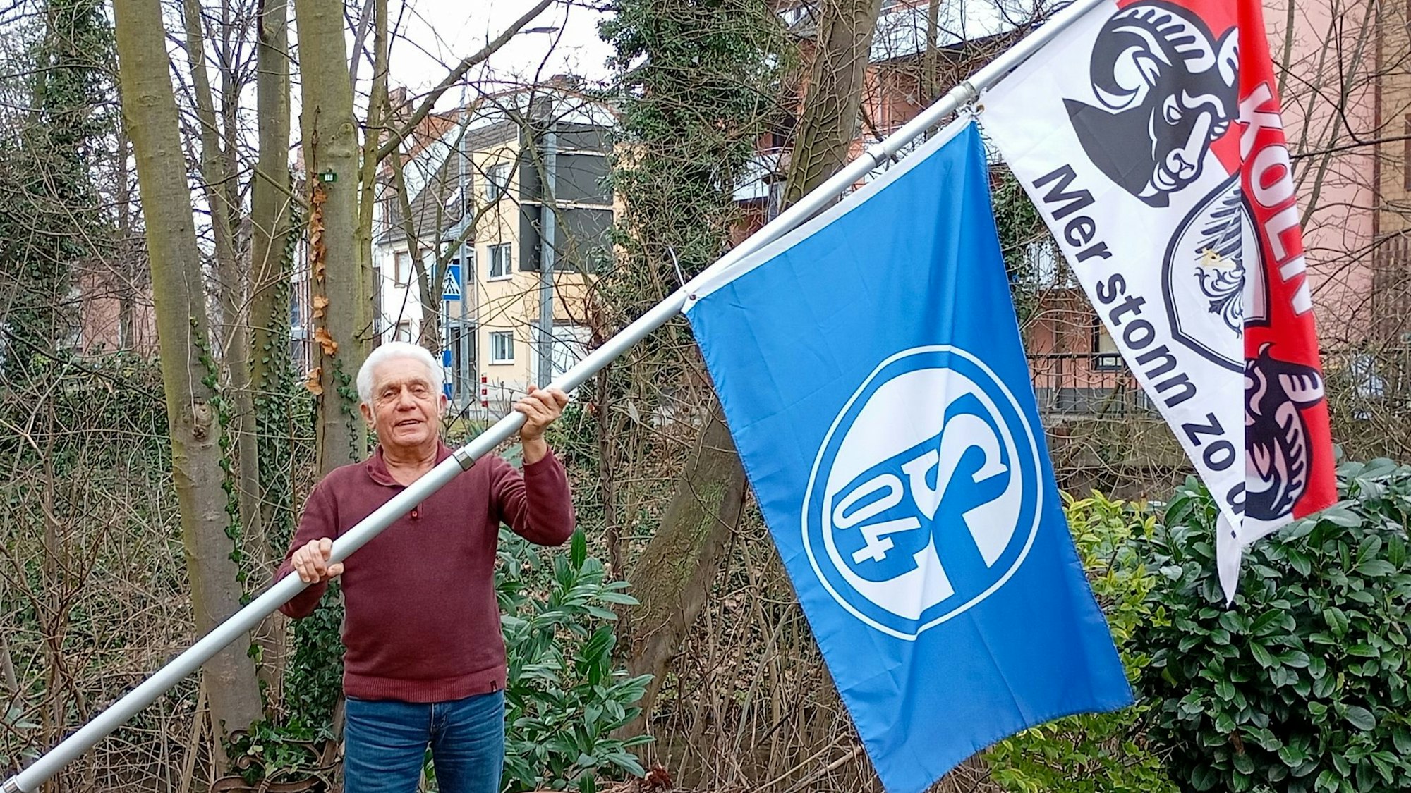 Das Foto zeigt einen Mann mit zwei großen Flaggen an einer Fahnenstange.