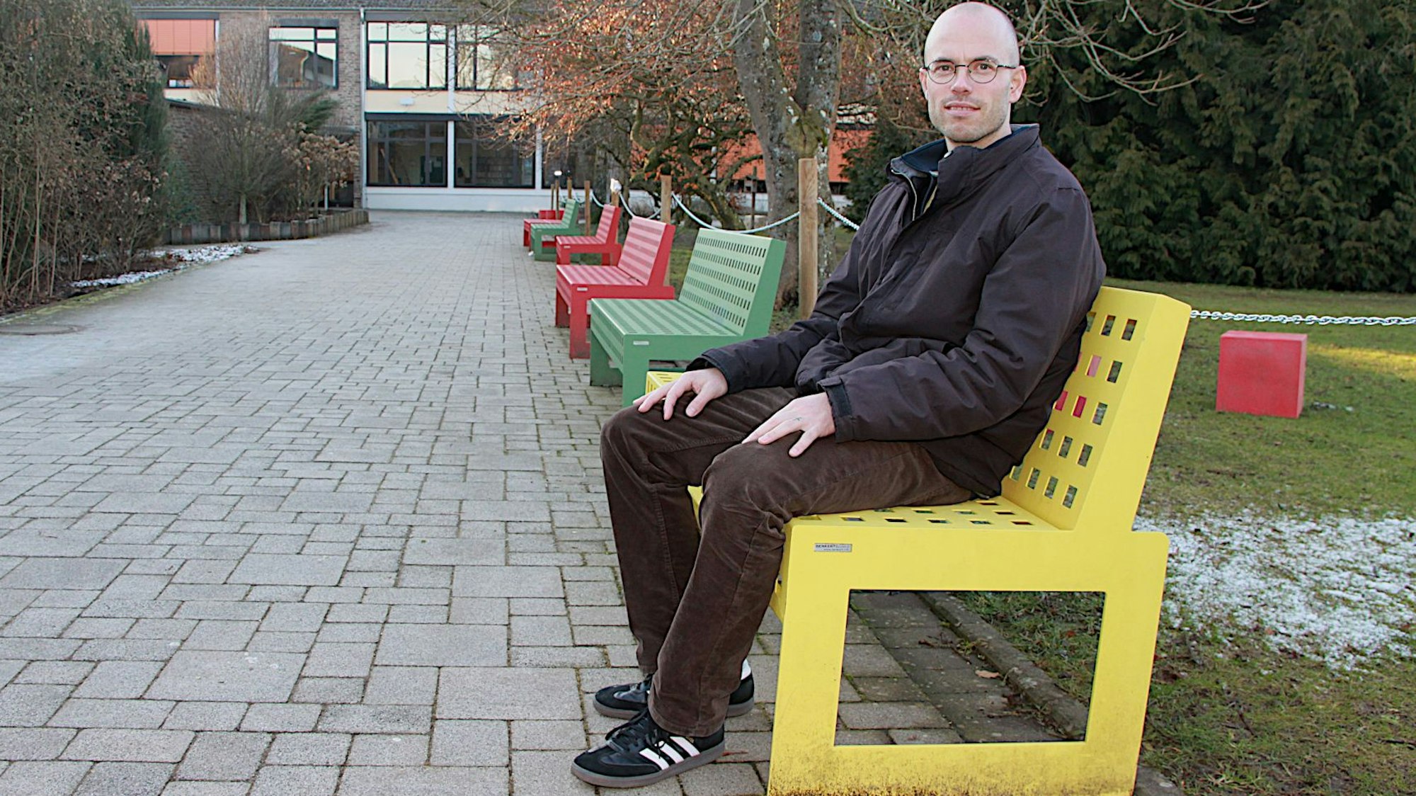 Pater Philipp Sauter sitzt auf einer Pausenbank.