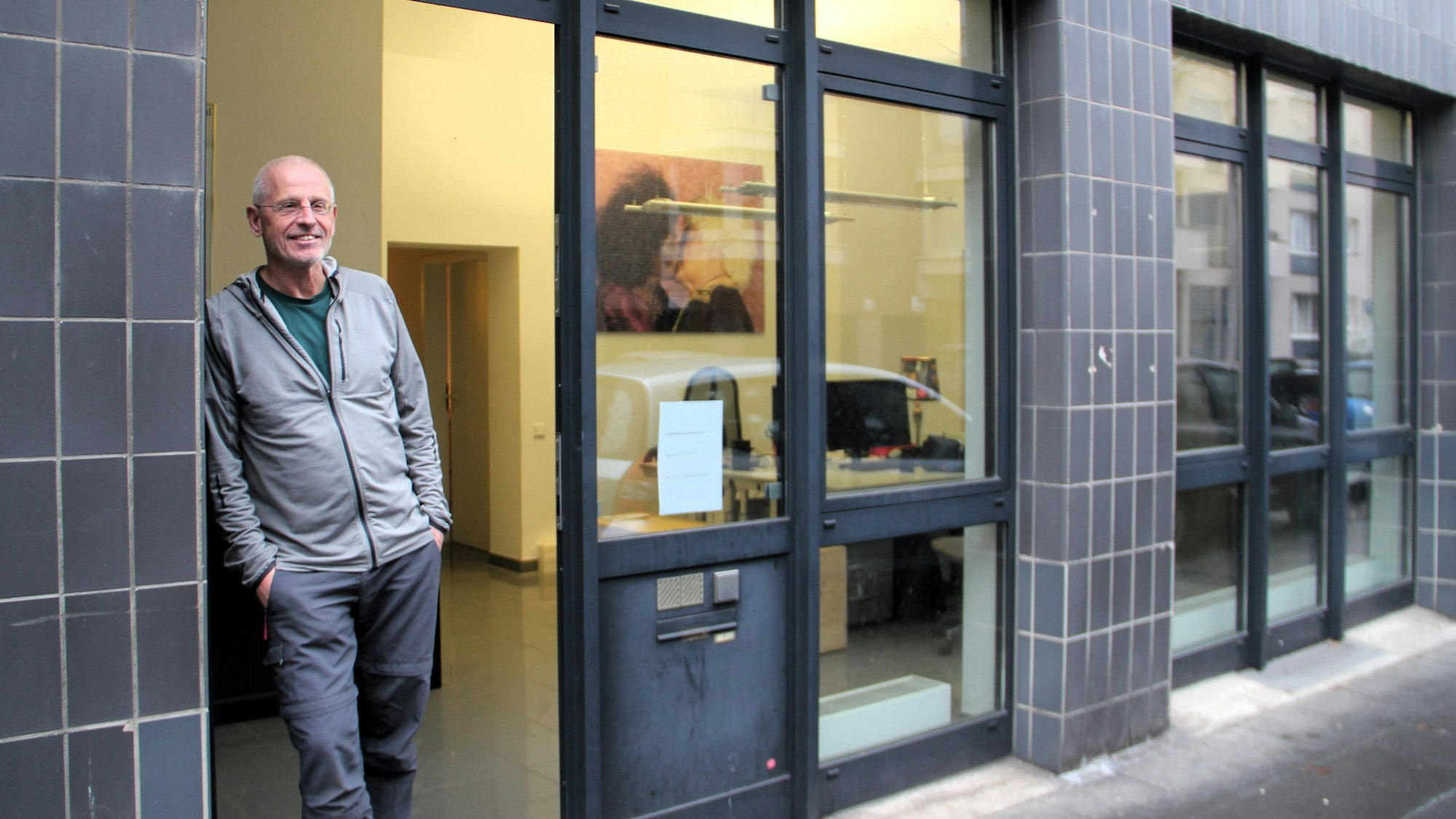 Ein Mann steht vor einem Büro mit hohen, dunkelgrauen Glasfassaden.