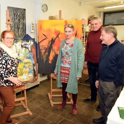 Das Foto zeigt Dozenten und Organisatoren des Kunstbahnhofs vor bunten Bildern.