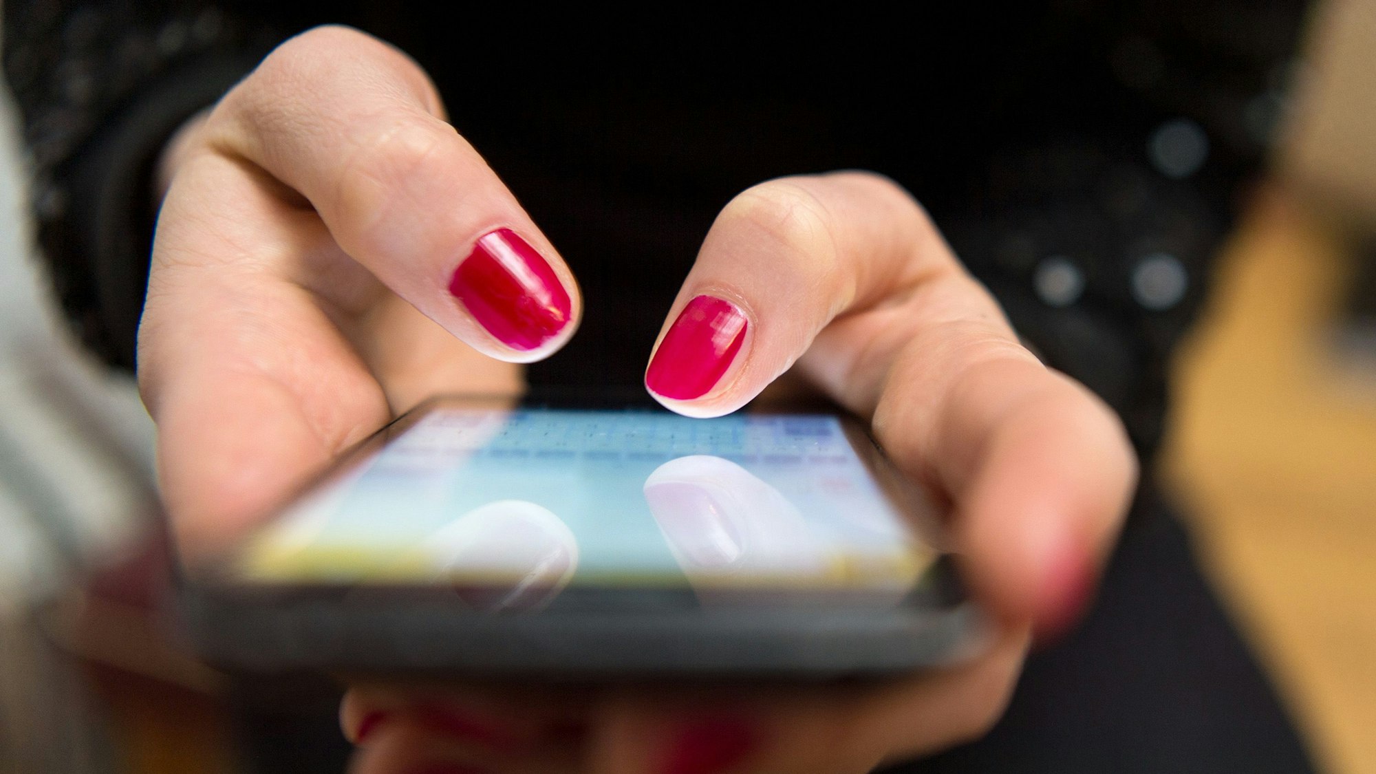 Eine Frau tippt auf einem Smartphone.