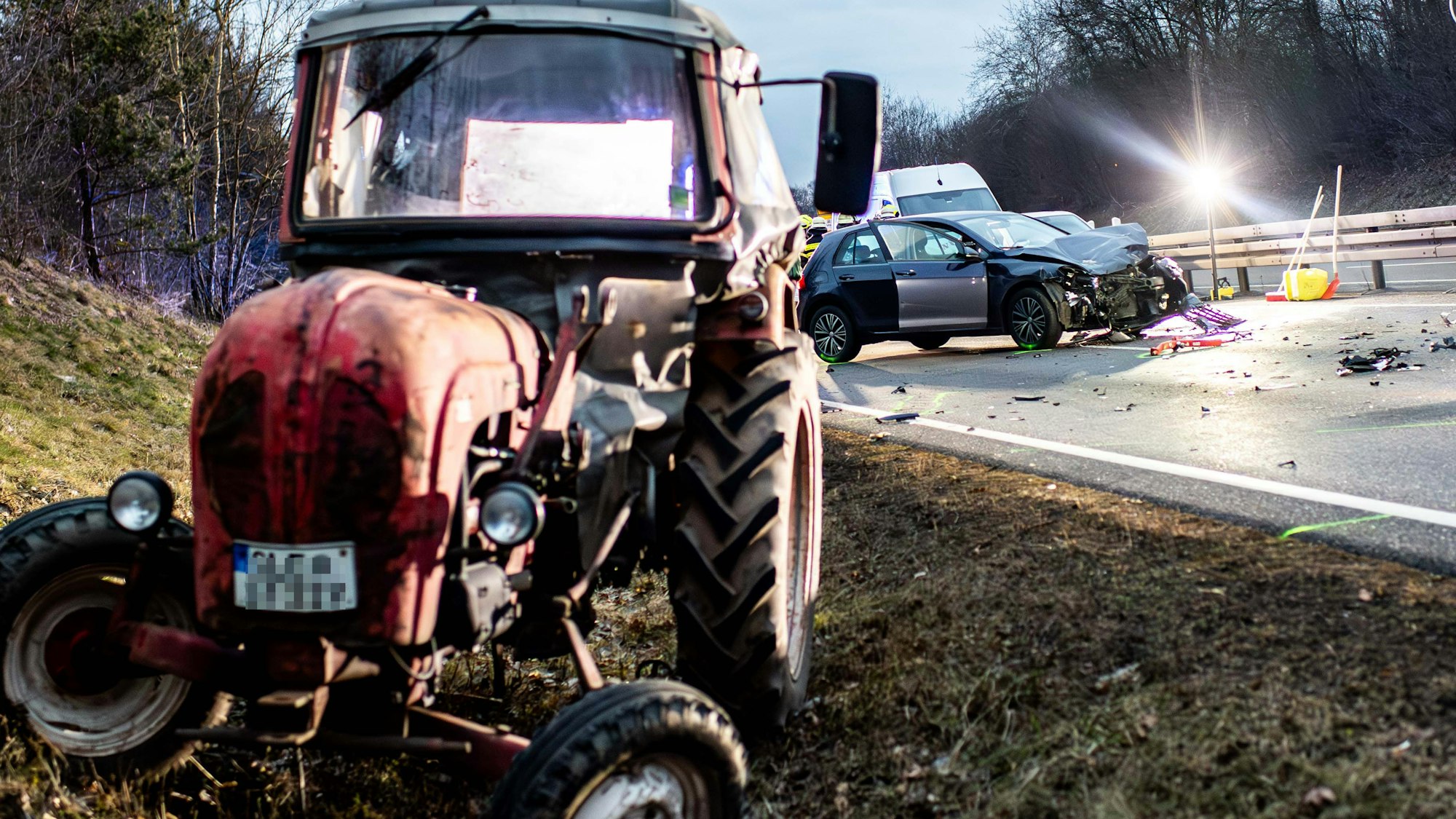 Das Bild zeigt den Traktor, der durch die Wucht des Aufpralls in den Straßengraben geschoben wurde. Im Hintergrund ist das beschädigte Auto zu sehen.
