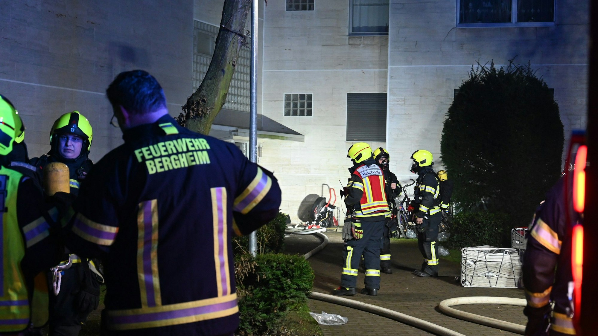 Das Bild zeigt mehrere Feuerwehrleute vor einem Mehrfamilienhaus.