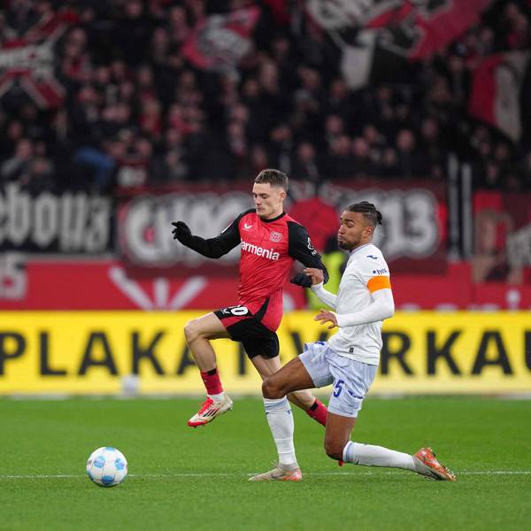 Das Bild zeigt einen Zweikampf zwischen Florian Wirtz und Kevin Akpoguma.