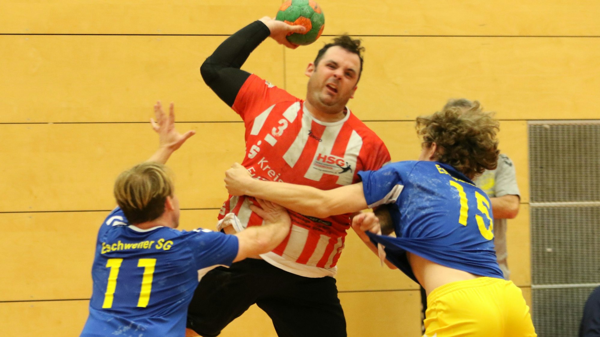 Handballer Niklas Müller steigt zum Pass auf und wird von zwei Gegnern attackiert.