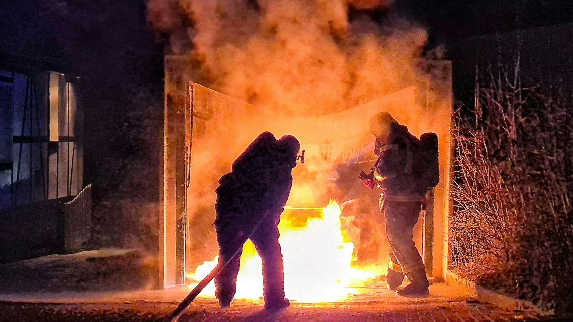Zwei Einsatzmänner vor dem Feuer.