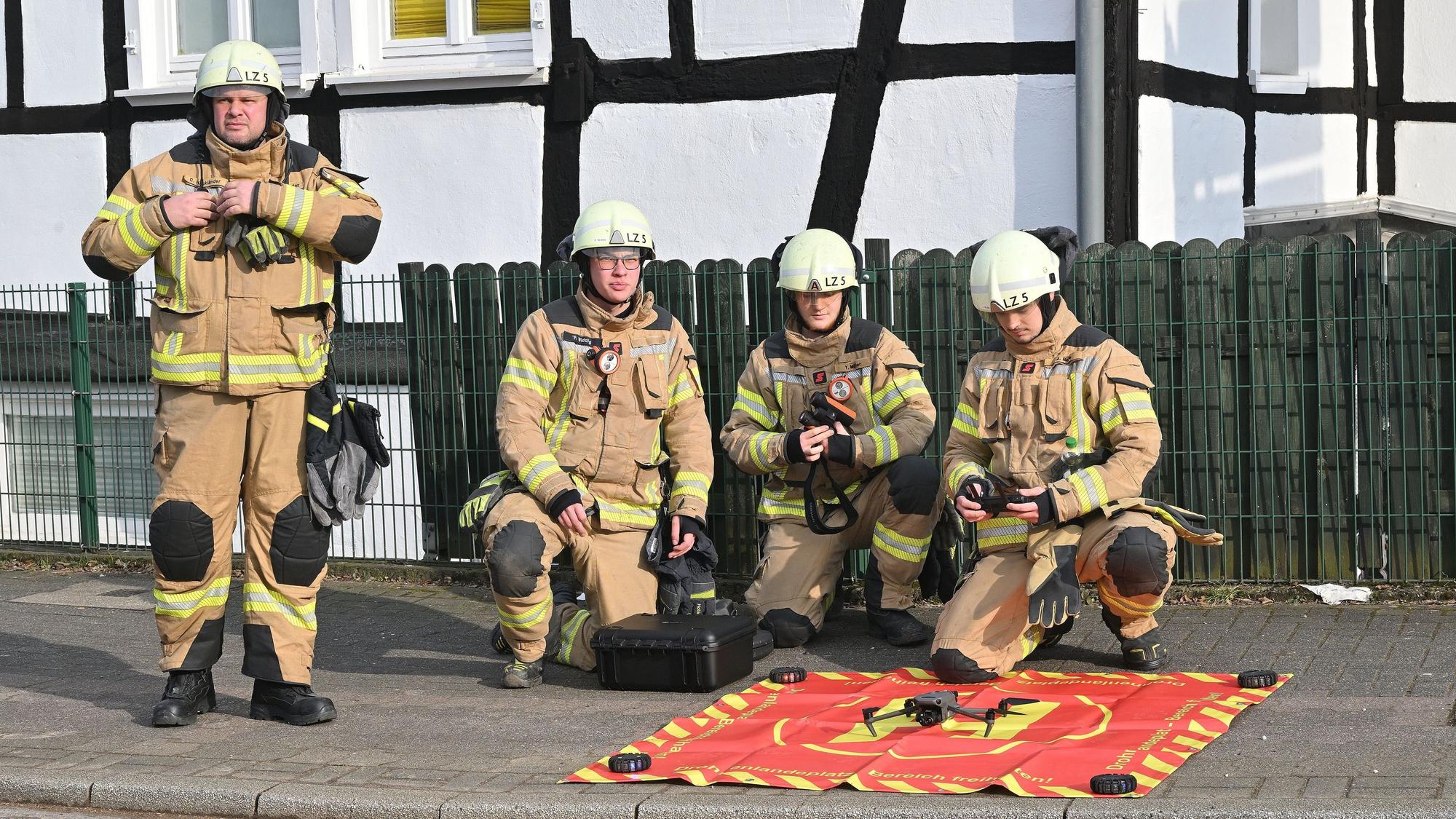 Eine Gruppe Feuerwehrleute kniet in Uniform auf dem Boden.