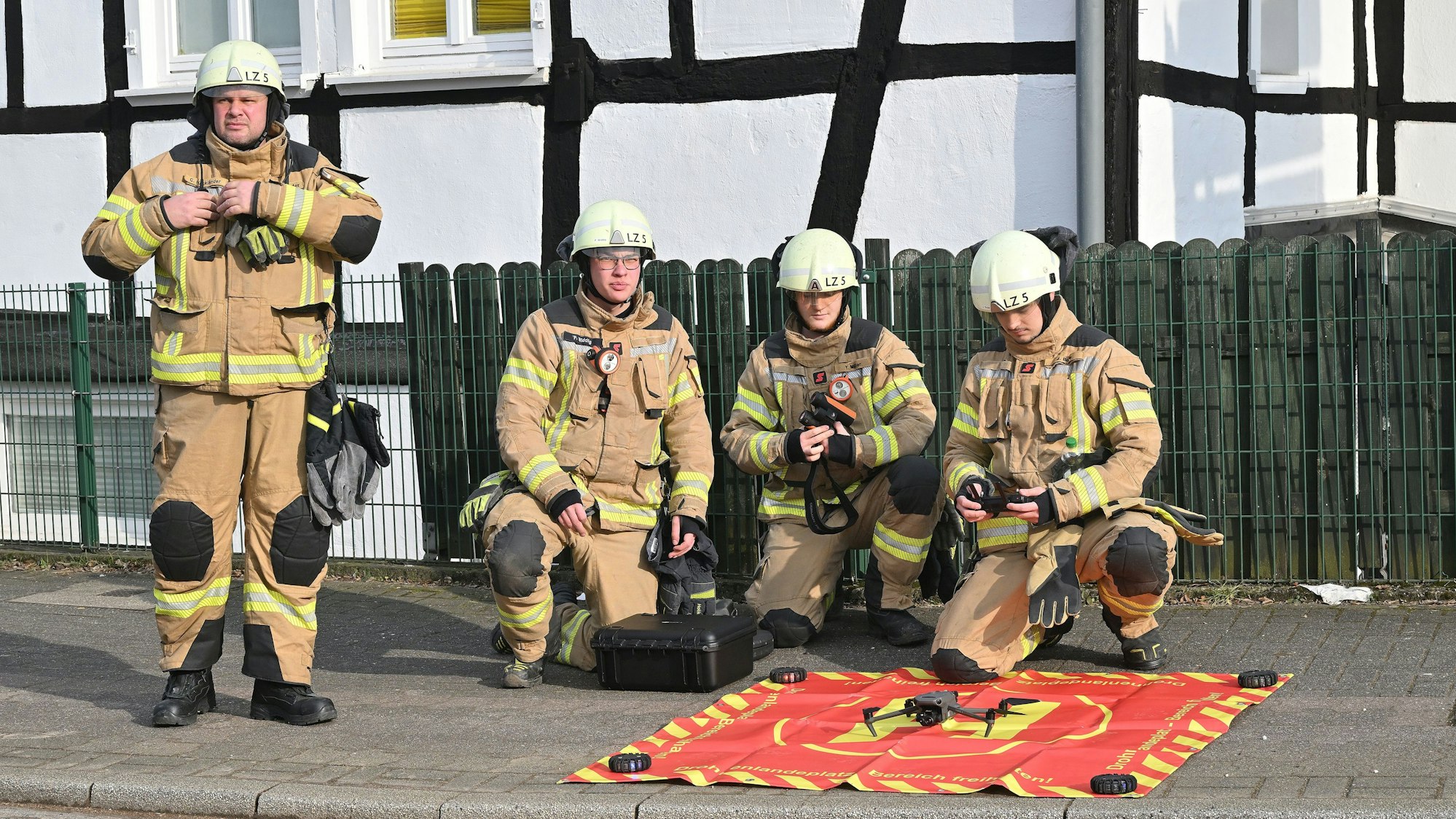 Eine Gruppe Feuerwehrleute kniet in Uniform auf dem Boden.