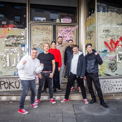 Stehen vor ihrem neuen Ladenlokal: Kasalla-Frontmann Basti Campmann (v.l.), Gitarrist Flo Peil, Managerin Kim Gerstenberg, Gastronom Till Riekenbrauk, Keyboarder Ena Schwiers, Drummer Nils Plum und Bassist Sebi Wagner.