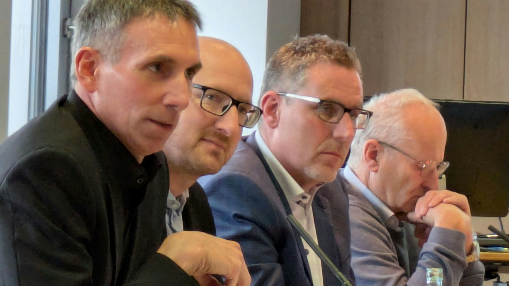 Marcel Wolter, Ingo Pfennings, Norbert Crump und Dr. Hans-Peter Schick sitzen am Tisch und blicken ernst.